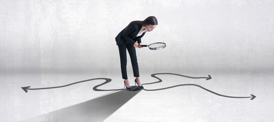 Young european businesswoman with magnifier and arrows on concrete background. Success, leadership, choice and direction concept. - obrazy, fototapety, plakaty