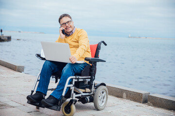 a man with disabilities in a wheelchair talking on a smartphone