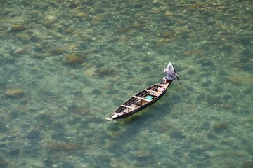 Fishing in transparent water of Dawki River in Meghalaya, India. River has crystal clear water in a...