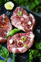 Fototapeta na wymiar Raw meat steaks with spices and basil. Pork steaks.
