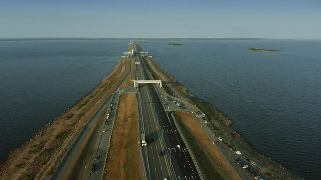 Aerial view of a modern highway, trucks and cars drive across the Baltic sea in the evening. Saint Petersburg, Russia