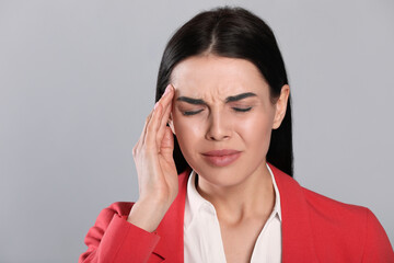 Woman suffering from migraine on grey background