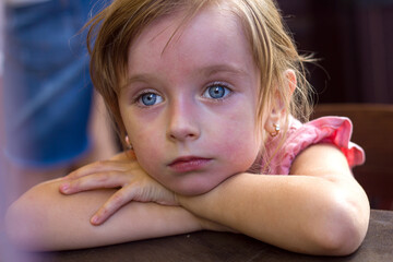 Portrait of a beautiful little girl child with reddened face and tired sad expression, feeling...