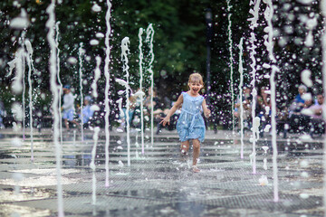happy little girl running under splashing water