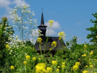 old wooden church surrounded by tall grasses and flowers