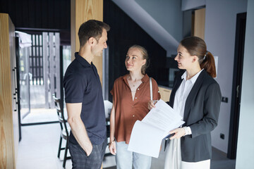 High angle portrait of young couple talking to real estate agent while buying new house, copy space