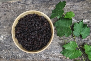 Dried black currant berries and green leaves grapes on wood table  background.