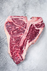 Raw T-bone or porterhouse Steak on kitchen table. White background. Top view