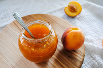 Peach jam in a glass jar on the table.
