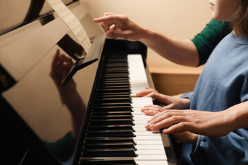 Young woman with child playing piano, closeup. Music lesson