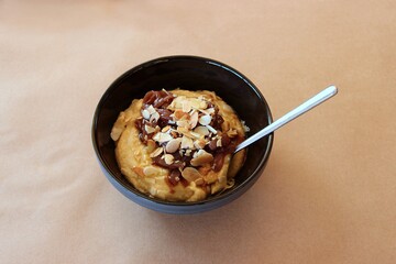 Fava (Puree yellow lentils) with caramelized onions and roasted almond flakes Greek traditional dish, isolated on brown baking paper. Selective focus
