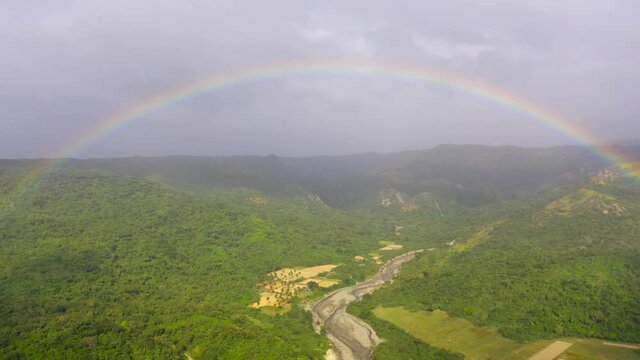 Rainbow over the river in the highlands. Mountains covered by rainforest, Luzon Island, Philippines. Summer and travel vacation concept.