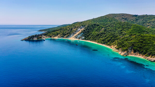 Drone shot of the blue and turquoise sea of Gidaki beach in Ithaca with luxury boats moored at the front