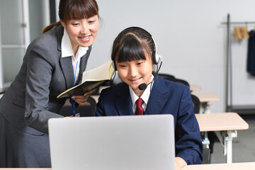 先生に教わりながらパソコン操作をする女子学生
