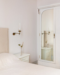 A part of bedroom interior with cozy bed and vintage wardrobe with mirror. Retro and classic style.