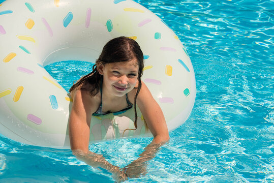 cute little girl playing in the pool with her inflatable ring