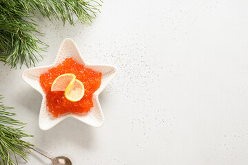 Red caviar served in bowl as sea star on white background for Christmas, New Year holidays party....