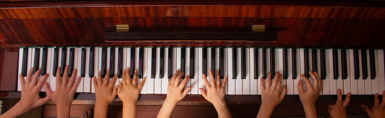 Young kids sitiing at wooden piano, top view