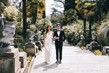 A beautiful married young couple in love in elegant wedding clothes walking posing and hugging on a...