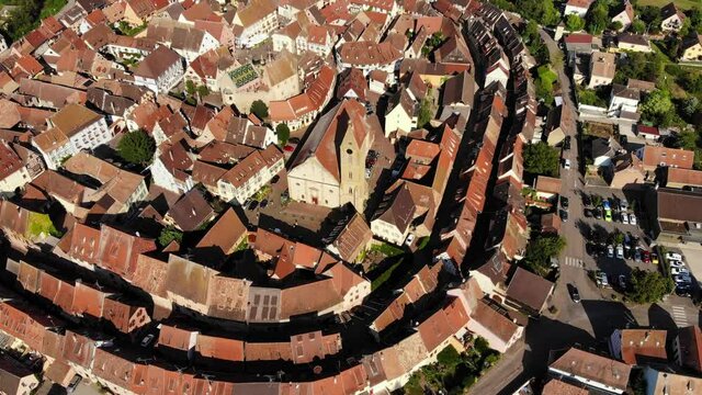 Church with tower in small town surround with old buildings, aerial shot of Eguisheim. Famous village located at Haut-Rhin region of France, part of Alsace Wine Route