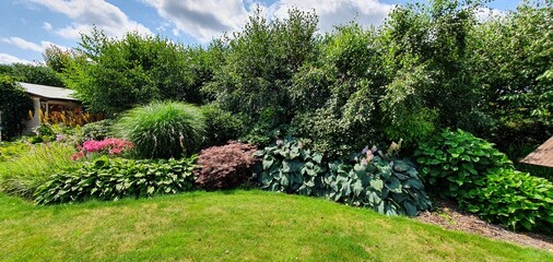 Piekny ogród z drewnianym domkiem i zielony trawnik