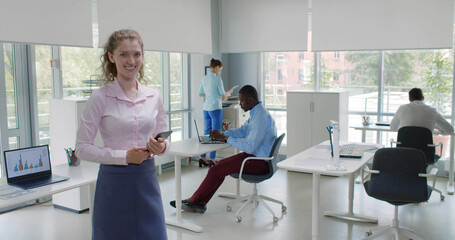 Portrait of young businesswoman using tablet in office and smiling at camera