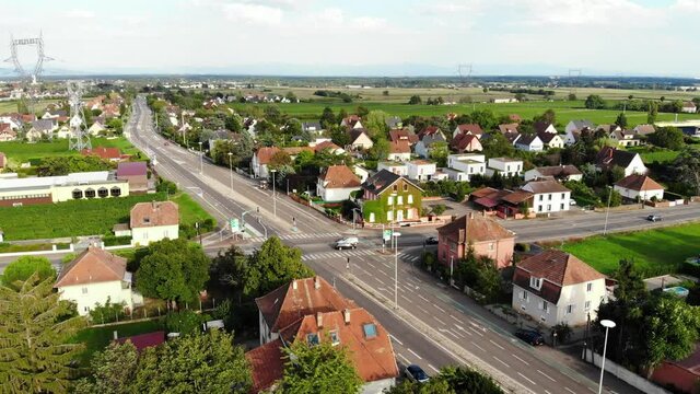 Large roads intersection at little French town, aerial shot. Wide highway to Colmar city comes through small Wintzenheim settlement. Traditional two-storey mansions seen around