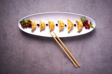 plate of japanese ravioli with chopsticks on stone background