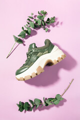 Chunky sole green trainer sneaker with eucalyptus branches framing it, on pink, top view - flatlay - 447279312