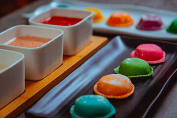 Sorrentinos de colores con salsa de colores en una mesa de marmol. Pasta 