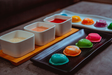 Obraz na płótnie Canvas Sorrentinos de colores con salsa de colores en una mesa de marmol. Pasta 