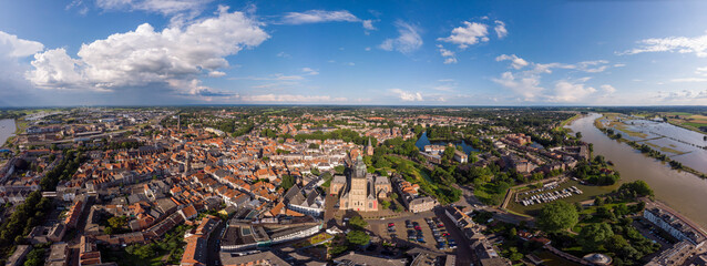 Wide cityscape aerial panorama of the Dutch medieval Hanseatic city of Zutphen in The Netherlands with the Walburgiskerk cathedral tower lit up in sunlight in urban landscape.