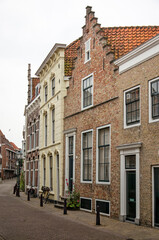 Fototapeta na wymiar Vlissingen, The Netherlands, July 24, 2021: curving street in the old town lined with traditional facades in brick and plaster