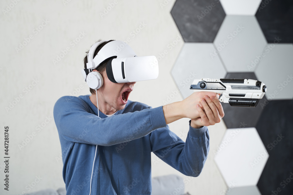 Wall mural man with virtual reality headset and blaster is playing game.
