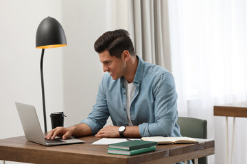 Man with laptop studying at table in library