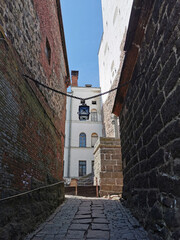A narrow passage with a lantern suspended on chains, between the stone walls of the Vyborg Castle...