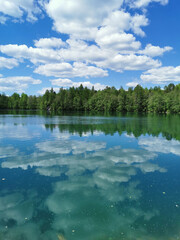 The shore of the lake is bright with clear water, in which you can see the marble on the bottom and reflect the sky with clouds, in the mountain park Ruskeala.