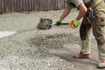 Work with a shovel at a construction site. A worker throws cement and gravel with a shovel.