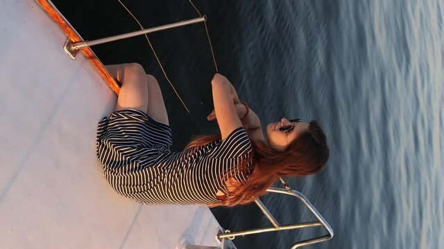 travel on a yacht. a young girl sits aft of a white yacht. vertical video.