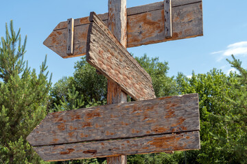 Wooden direction signs on a pole. Layout. Empty arrows of a village street post. An empty wooden sign on a background of trees for a design in the concept of your work.