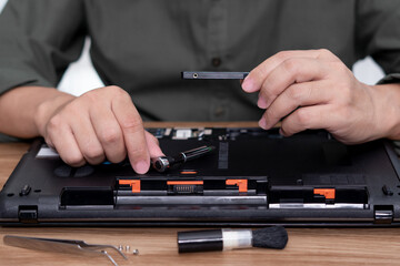 A man hold hard disk with screwdriver in hand repair laptop computer upgrade and cleaning and tool computer repair on the table