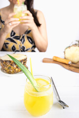 Refreshing homemade pineapple juice with ice. Girl at a table drinking a pineapple juice. Cool drink for summer. Healthy drink with vitamins