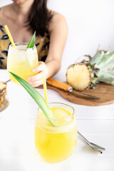 Refreshing homemade pineapple juice with ice. Girl at a table drinking a pineapple juice. Cool drink for summer. Healthy drink with vitamins