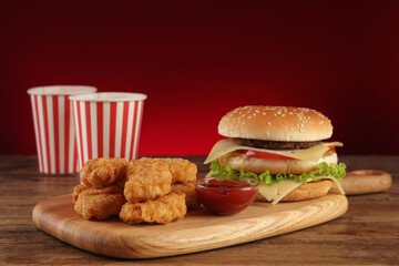 Delicious fast food menu on wooden table against red background