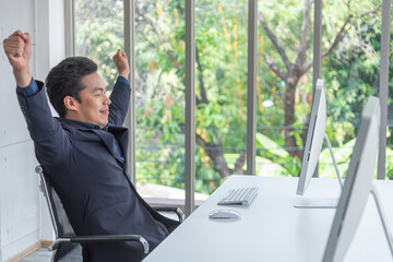 Asian handsome man looking happy while use computer in office