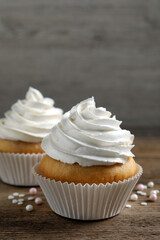 Delicious cupcakes with cream on wooden table