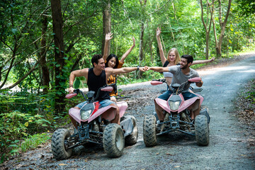 young couple or friend happily touches their hands while riding an ATV in the forest © Mrzproducer