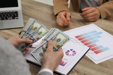 Fototapeta premium Cashier counting money at desk in bank, closeup