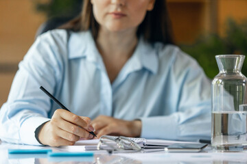 Cropped image of young woman, business lady during working office day. Using laptop, modern gadgets. Remote working. Workplace at office with PC, devices.