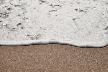Sea foam on the shore and wet sand. Travel photo